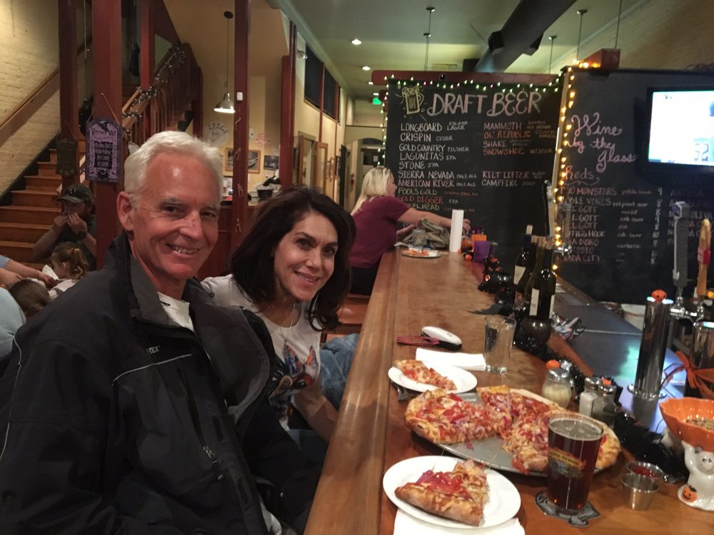 Two patrons seated at the Main Street Pizza bar with a pizza